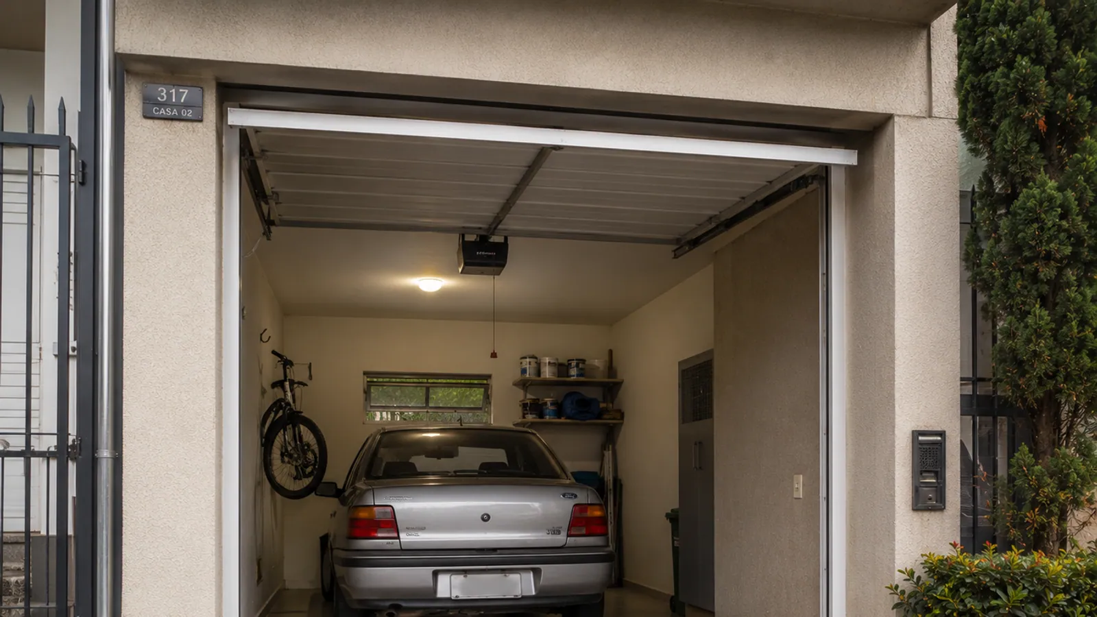 Garagem residencial em Curitiba com portão automático aberto e carro estacionado